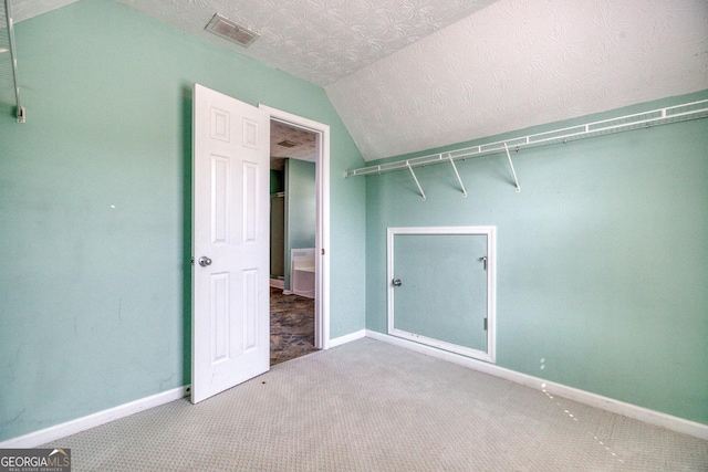 interior space with lofted ceiling, visible vents, a textured ceiling, and baseboards