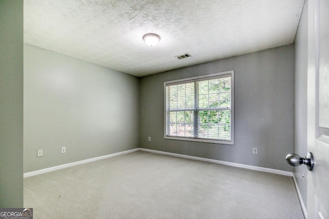 spare room featuring baseboards, a textured ceiling, visible vents, and carpet flooring