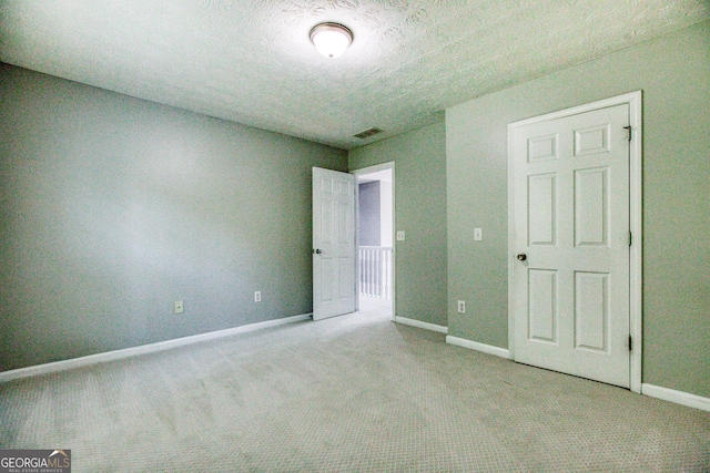 empty room featuring baseboards, a textured ceiling, visible vents, and light colored carpet