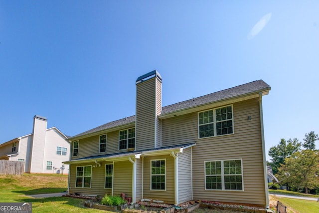 rear view of property featuring a chimney, fence, and a lawn