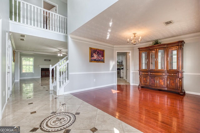 entrance foyer featuring a notable chandelier, baseboards, stairs, light wood-style floors, and ornamental molding