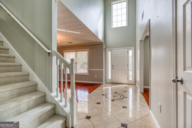 tiled entryway with baseboards, stairway, and a healthy amount of sunlight