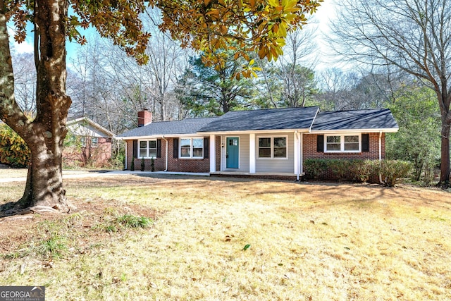 ranch-style home featuring a front yard, a chimney, and brick siding