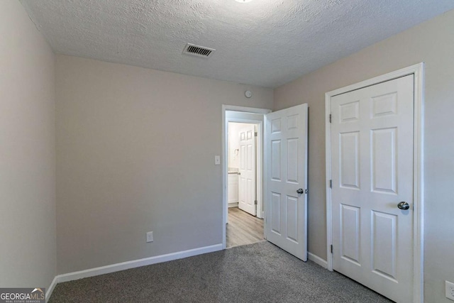 unfurnished bedroom with light carpet, baseboards, visible vents, and a textured ceiling