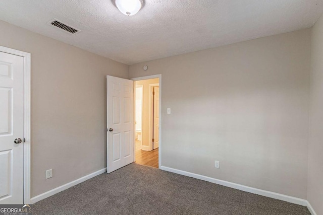 unfurnished bedroom featuring a textured ceiling, carpet flooring, visible vents, and baseboards