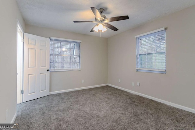 unfurnished bedroom featuring ceiling fan, multiple windows, carpet, and baseboards