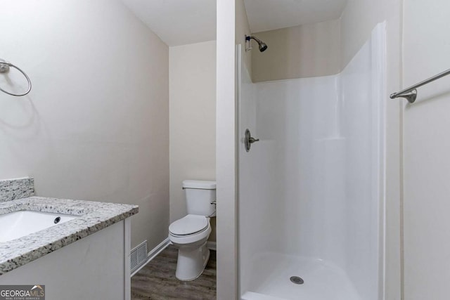 bathroom featuring a stall shower, visible vents, toilet, wood finished floors, and vanity