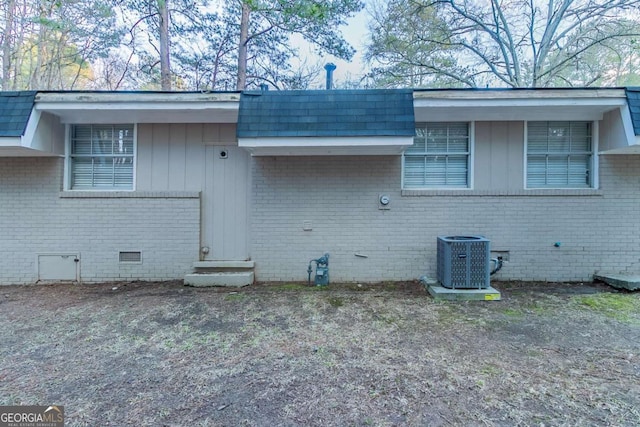 view of property exterior with entry steps, roof with shingles, crawl space, central AC, and brick siding