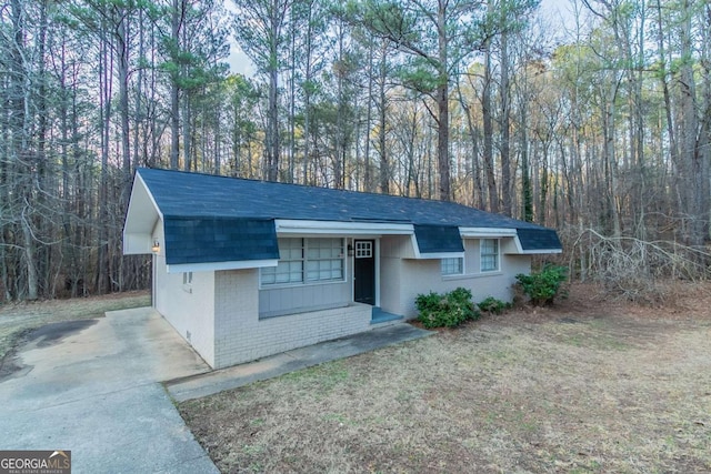 view of front of home with a shingled roof, a front yard, and brick siding