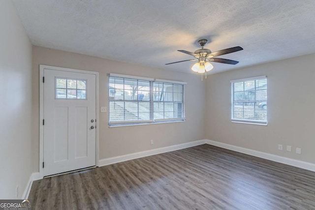 foyer entrance with dark wood finished floors, a textured ceiling, baseboards, and ceiling fan