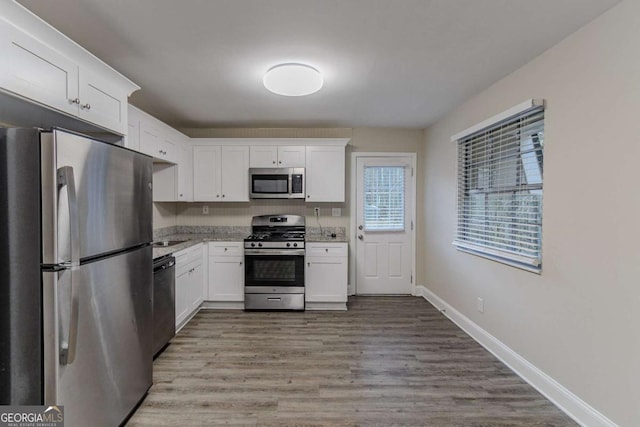 kitchen featuring light wood-style floors, white cabinetry, appliances with stainless steel finishes, and baseboards