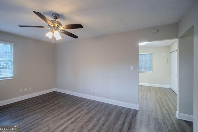 unfurnished room with ceiling fan, a textured ceiling, baseboards, and dark wood-type flooring