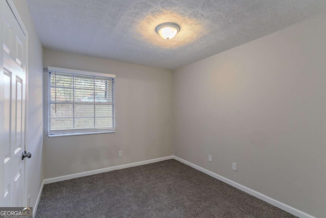 empty room with baseboards, dark carpet, and a textured ceiling