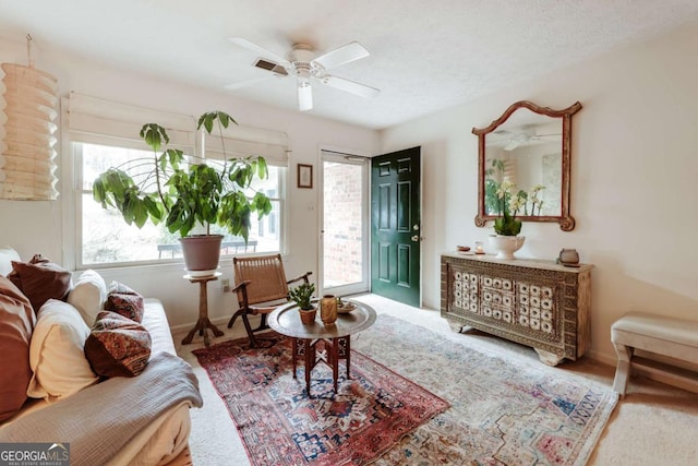 living area featuring a ceiling fan and a textured ceiling