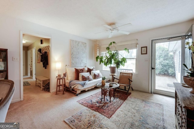 living area featuring light carpet, ceiling fan, and baseboards