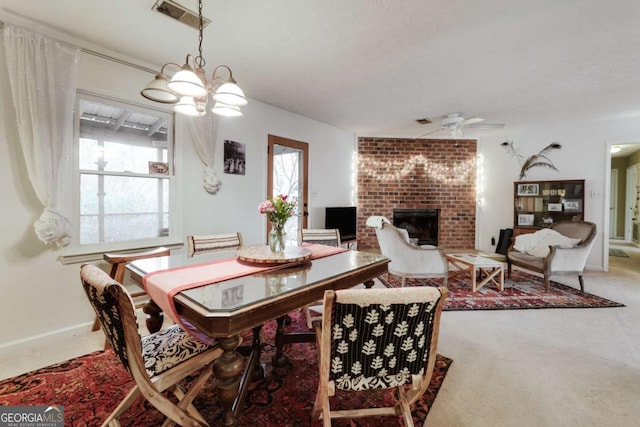 carpeted dining area featuring a brick fireplace, visible vents, baseboards, and ceiling fan with notable chandelier