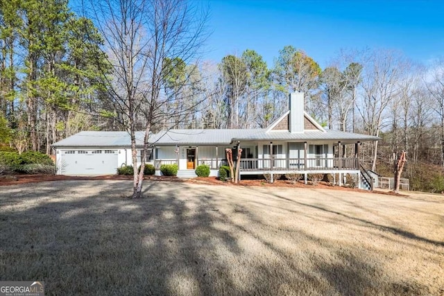 view of front facade featuring a garage, driveway, a porch, and a chimney