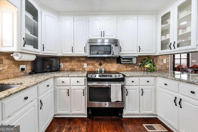 kitchen featuring visible vents, appliances with stainless steel finishes, glass insert cabinets, dark wood-type flooring, and white cabinetry