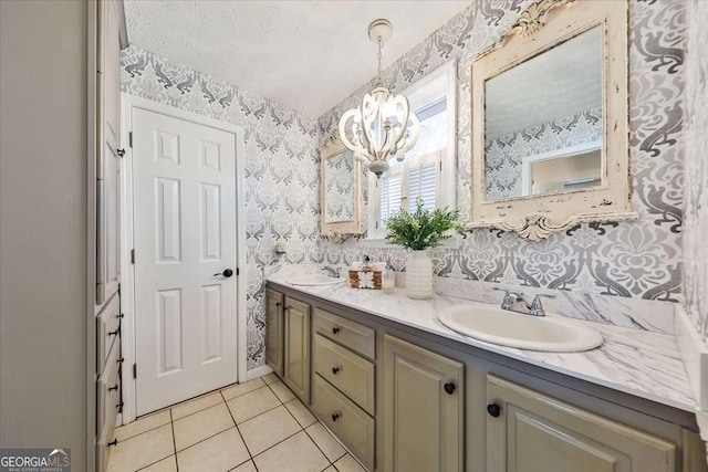 bathroom featuring double vanity, wallpapered walls, a sink, a textured ceiling, and tile patterned floors