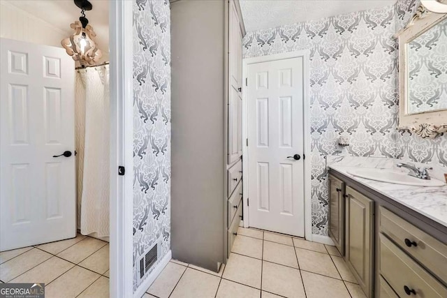 bathroom featuring tile patterned flooring, vanity, and wallpapered walls