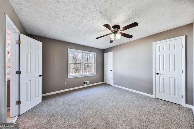 unfurnished bedroom featuring baseboards, visible vents, ceiling fan, and carpet flooring