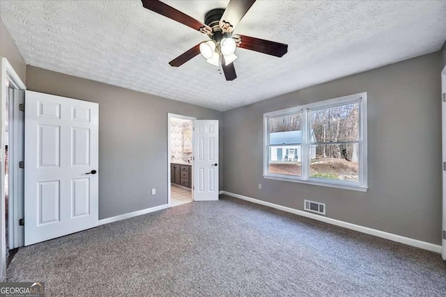 unfurnished bedroom featuring baseboards, visible vents, connected bathroom, light colored carpet, and a textured ceiling