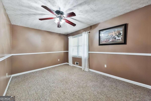 carpeted empty room with a textured ceiling, visible vents, a ceiling fan, and baseboards