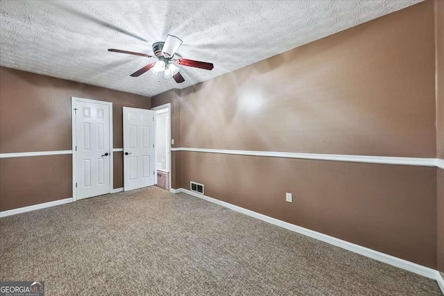 unfurnished bedroom featuring visible vents, a textured ceiling, baseboards, and carpet flooring