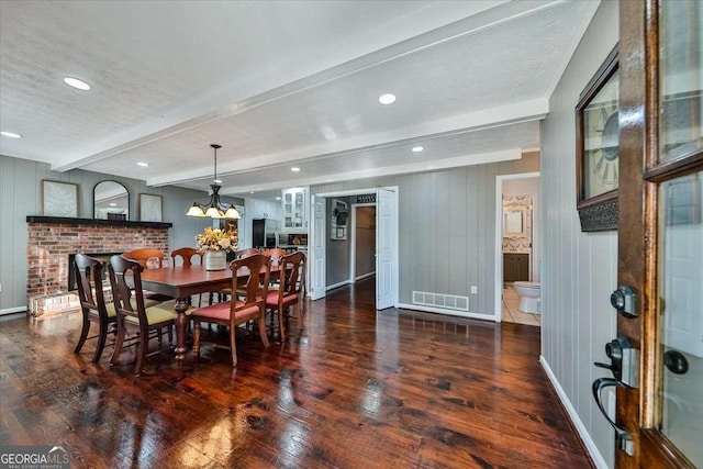 dining area with beam ceiling, visible vents, dark wood-type flooring, a textured ceiling, and baseboards