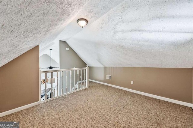 additional living space with a textured ceiling, carpet, visible vents, and baseboards