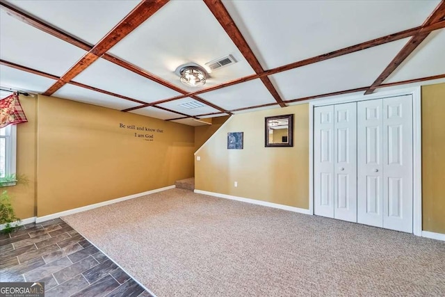 additional living space with visible vents, dark carpet, and baseboards