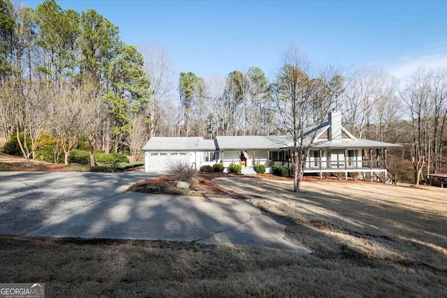 view of front of house featuring driveway, a chimney, and an attached garage