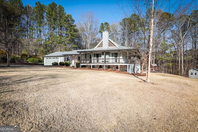 ranch-style home with driveway, a garage, a chimney, a porch, and a front yard