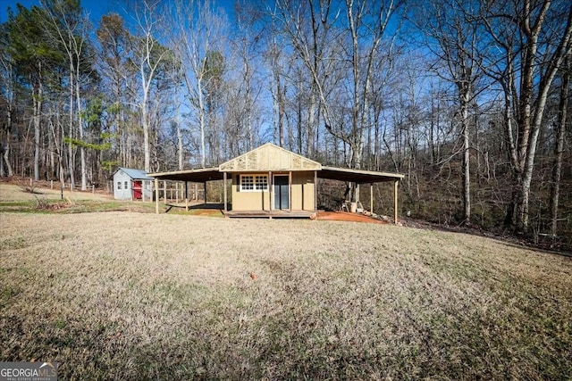 view of front of property with driveway, an attached carport, an outdoor structure, a shed, and a front lawn