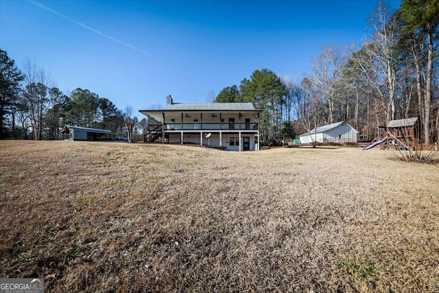 rear view of property with a chimney, a lawn, a deck, and a playground