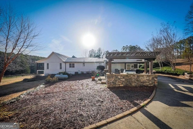 ranch-style house featuring metal roof, area for grilling, and a pergola