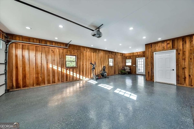 garage with wood walls, recessed lighting, and a garage door opener