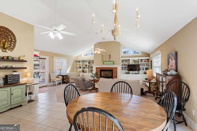 dining area with light tile patterned flooring, plenty of natural light, a fireplace, and ceiling fan with notable chandelier