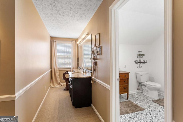 bathroom featuring a textured ceiling, vanity, toilet, and baseboards