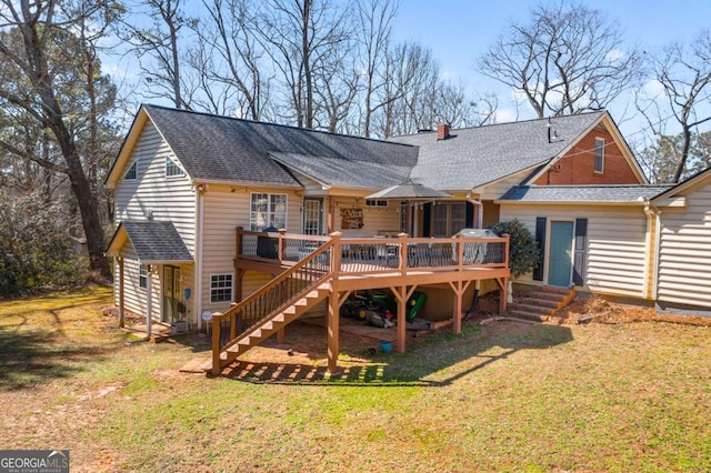 rear view of house featuring a shingled roof, a yard, stairway, and a deck