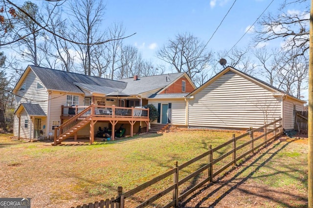 rear view of property featuring a yard, stairway, fence, and a deck