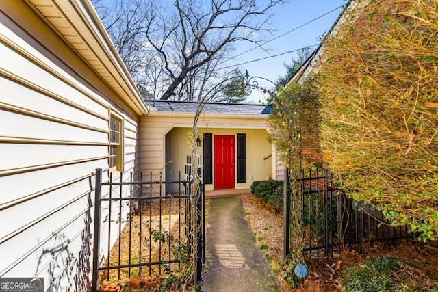 entrance to property featuring roof with shingles and fence