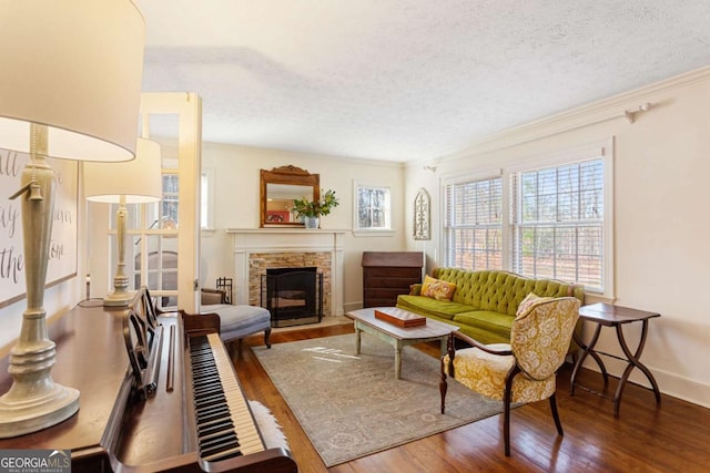 living area featuring baseboards, wood finished floors, crown molding, a textured ceiling, and a fireplace