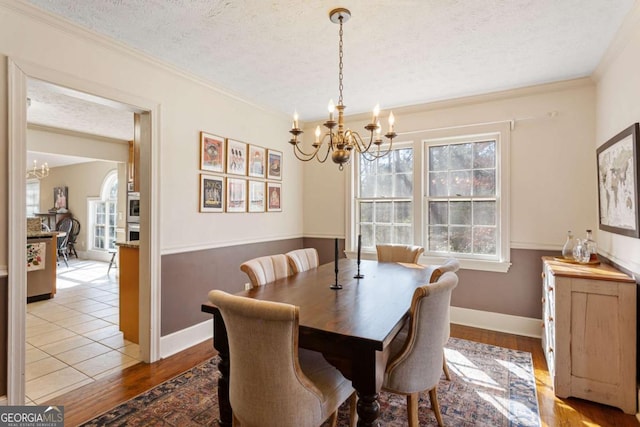 dining room with a chandelier, ornamental molding, a textured ceiling, and wood finished floors