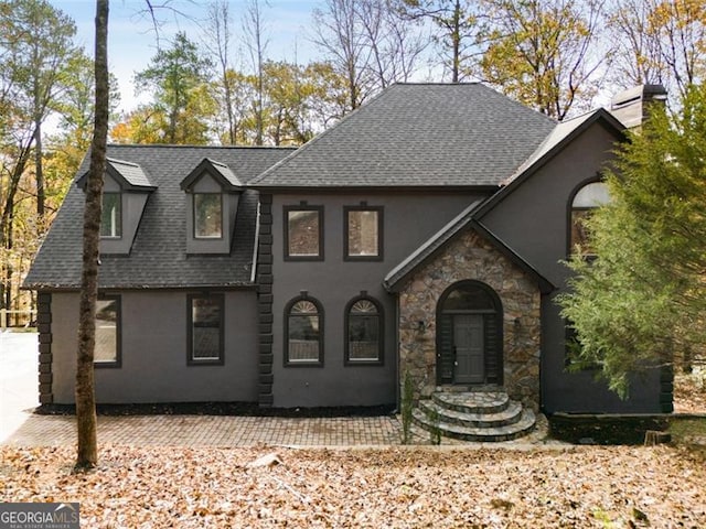 view of front of home with stone siding, a shingled roof, and stucco siding