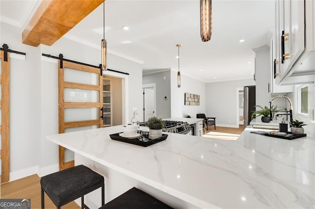 kitchen featuring light stone counters, a barn door, a sink, and decorative light fixtures