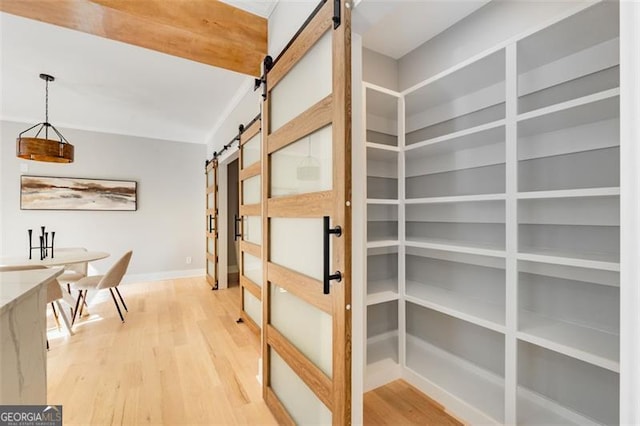 hallway featuring a barn door, baseboards, and wood finished floors