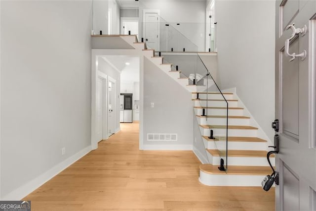 stairs featuring a towering ceiling, baseboards, visible vents, and wood finished floors