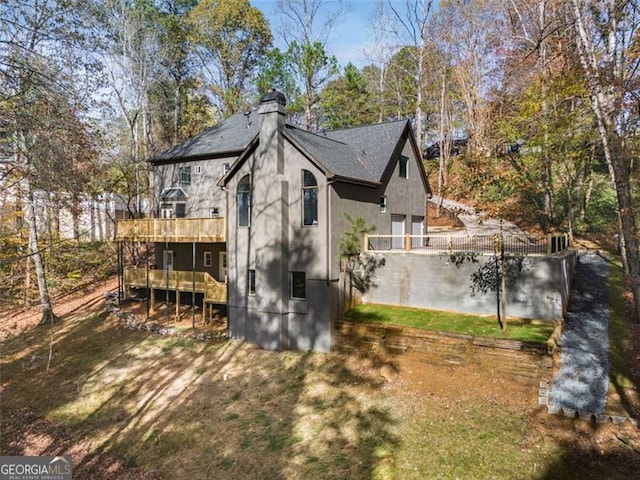 rear view of property with a chimney, a wooden deck, and stucco siding