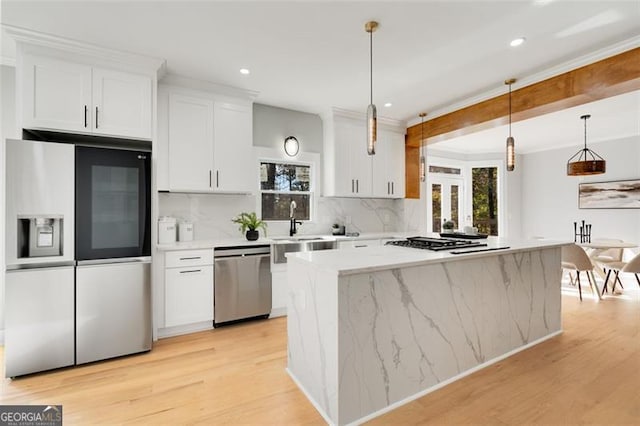 kitchen with stainless steel appliances, white cabinets, light countertops, a center island, and decorative light fixtures